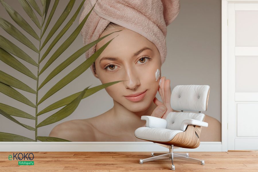 kobieta z ręcznikiem na głowie nakłada krem - fototapeta do salonu kosmetycznego