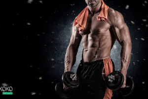 muskularny facet ze zdjętą koszulką pozuje z hantlami - fototapeta do siłowni, klubu fitness
