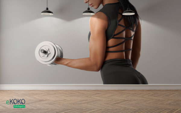 wysportowana brunetka w ciemnym stroju z hantlami ćwiczy mięśnie rąk - fototapeta do siłowni, klubu fitness
