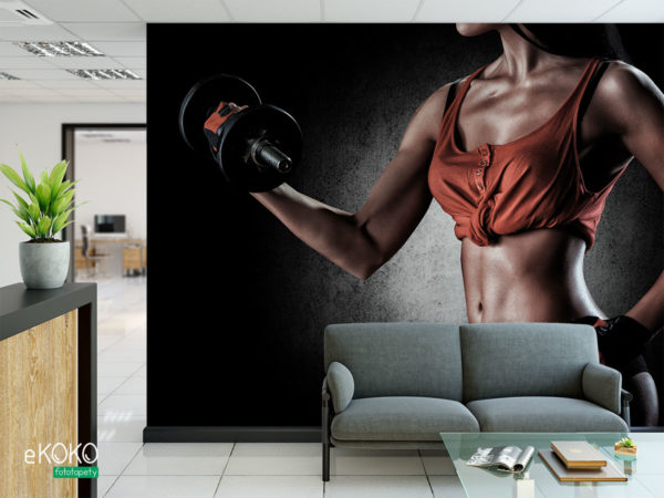 wysportowana brunetka w czarno-pomarańczowym stroju z hantlami - fototapeta do siłowni, klubu fitness