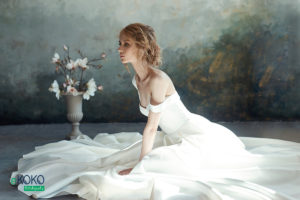 panna młoda w długiej białej sukni siedzi na podłodze – fototapeta do salonu ślubnego