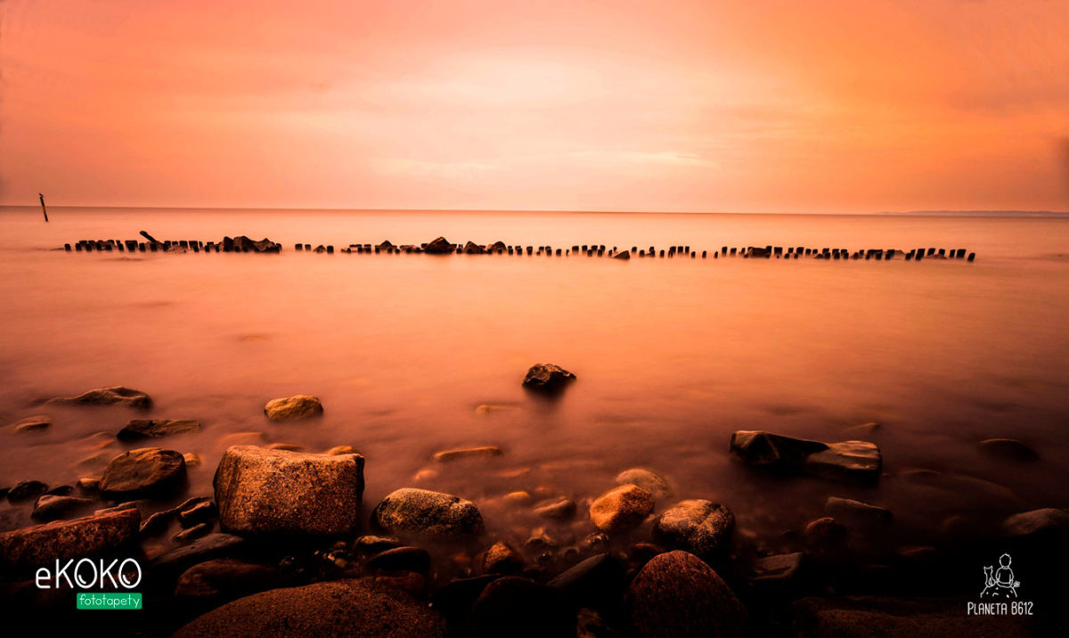 krajobraz falochron nad morzem w pomarańczowej poświacie - fototapeta
